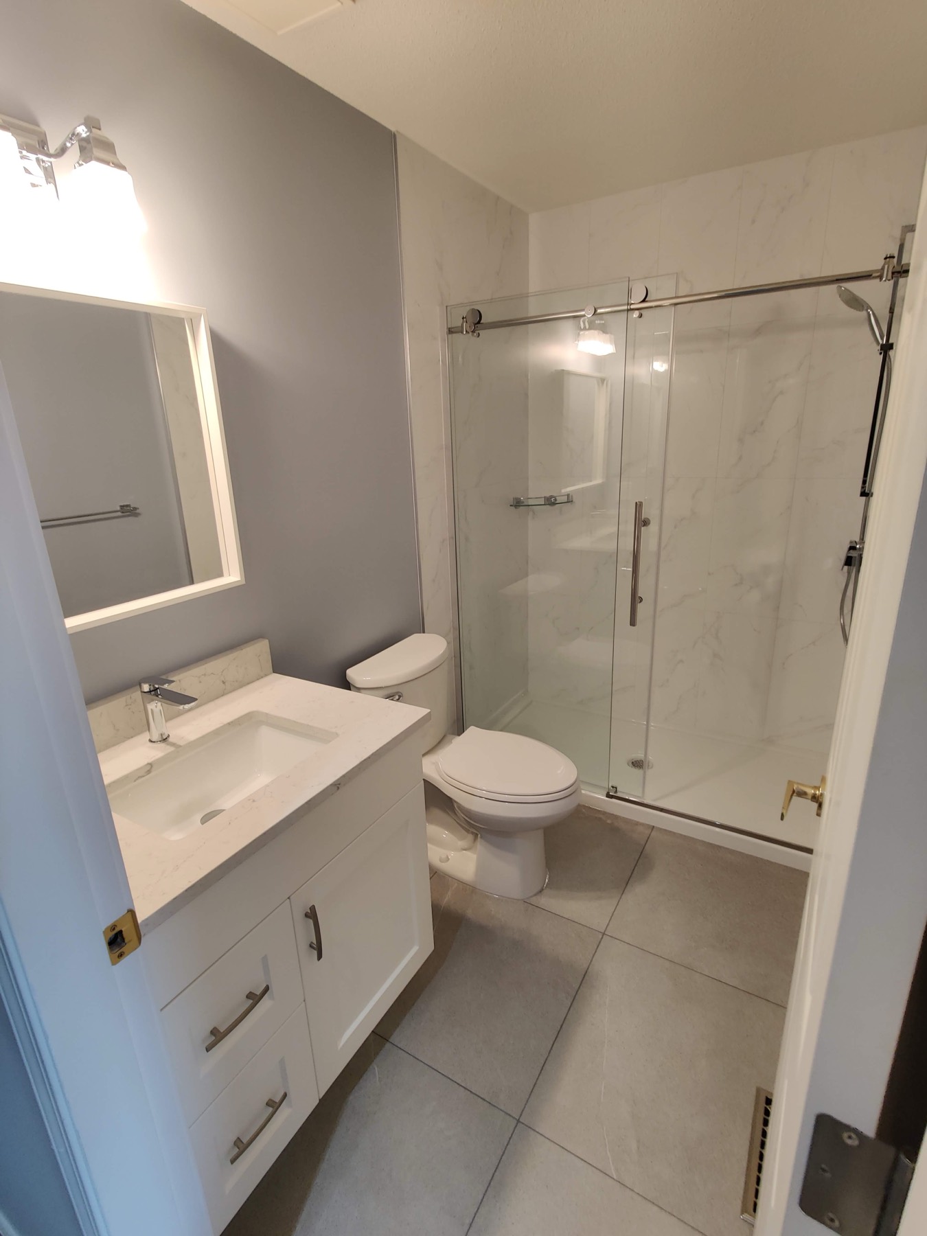 Bathroom with a glass shower, vanity and wide mirror