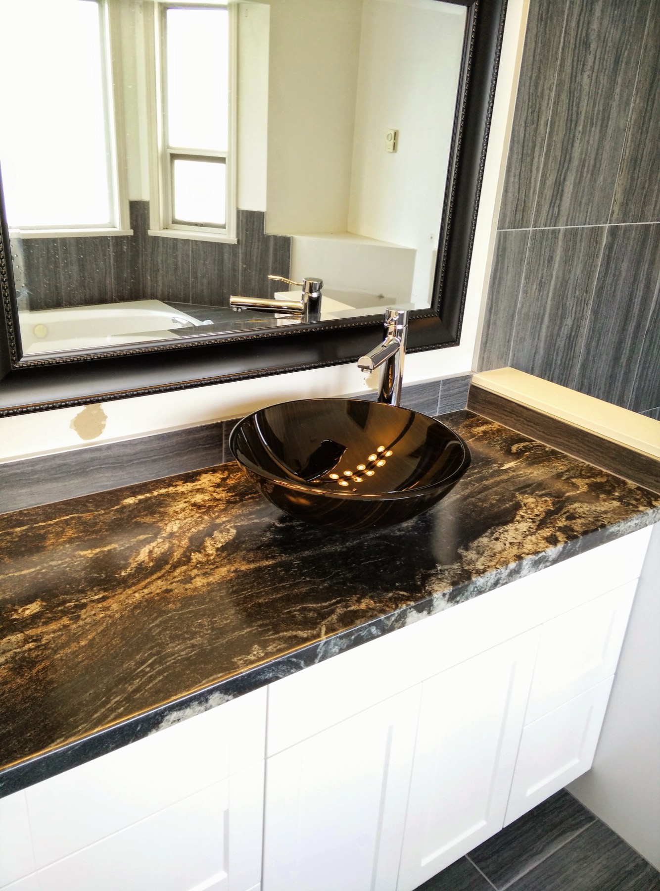 Vessel basin set on a dark patterned stone vanity top