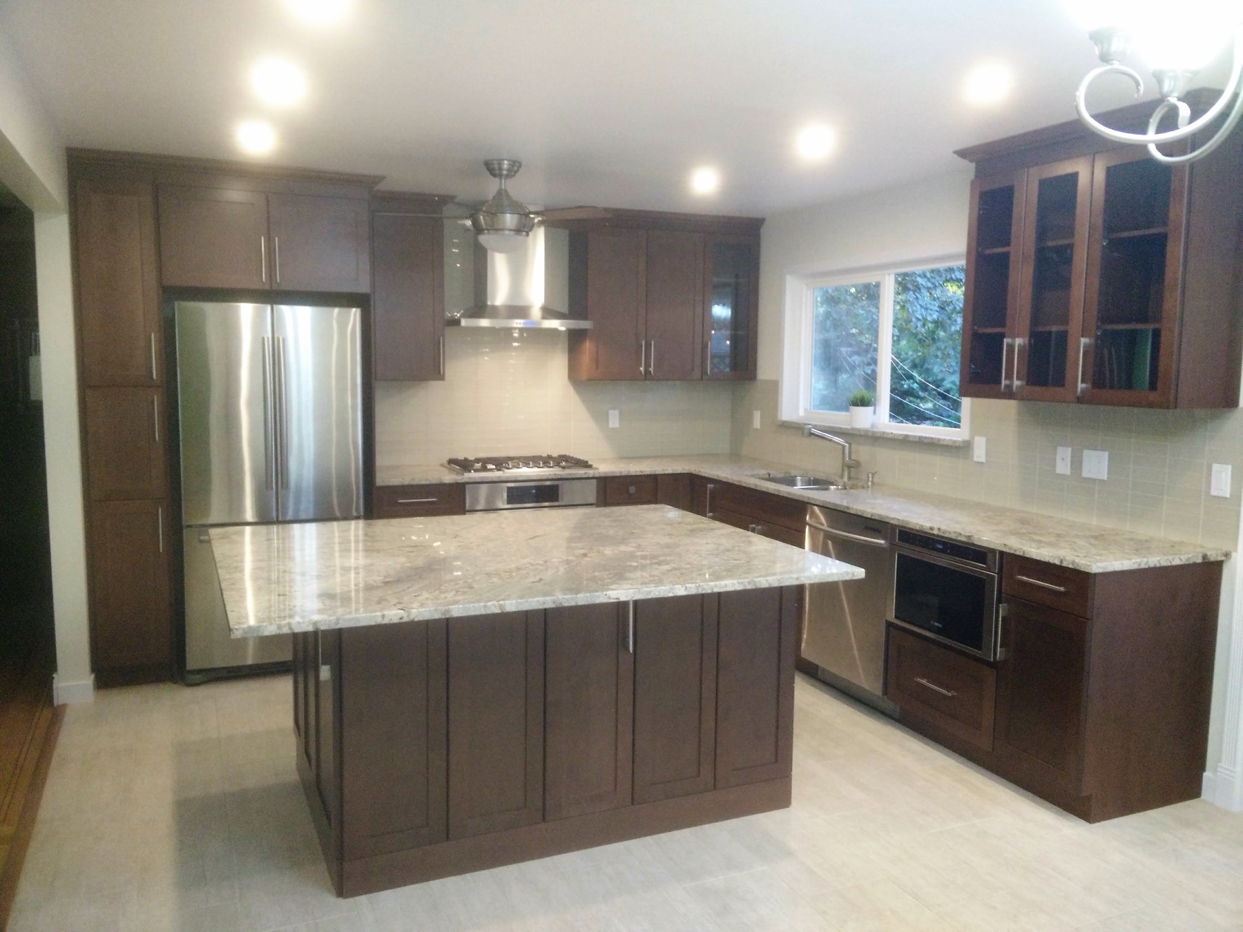 Renovated kitchen with a large island, dark cabinetry and stone counters