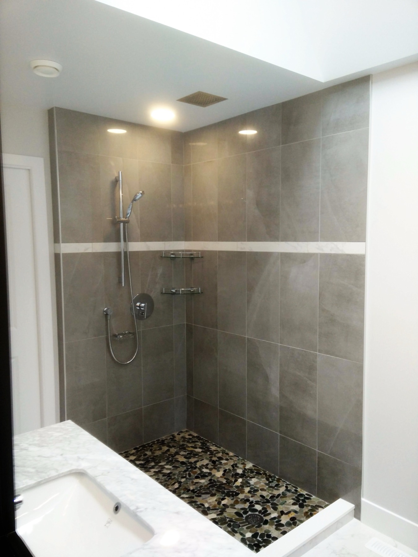 Tiled walk in shower with a pebble floor