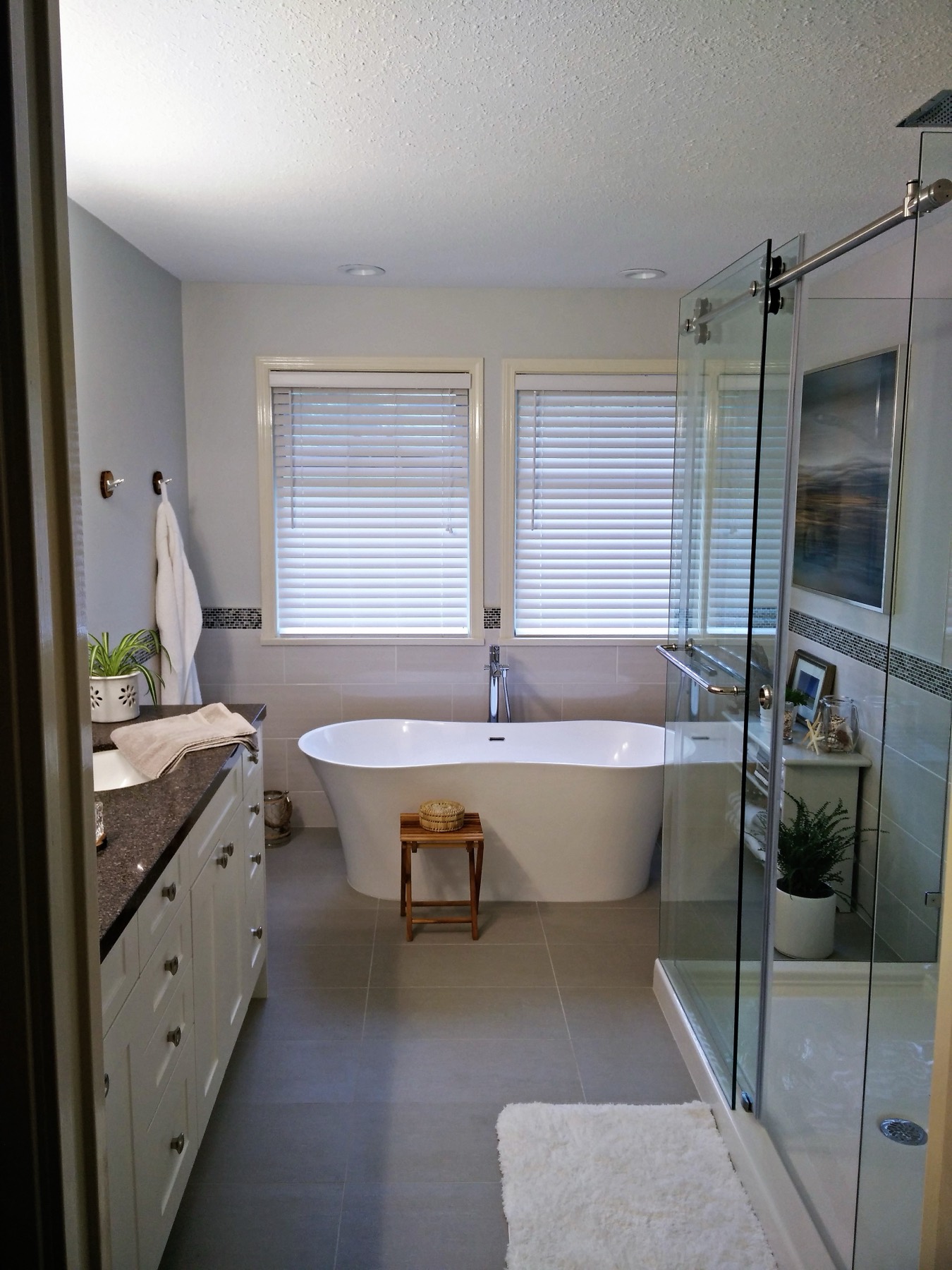 Renovated bathroom with a freestanding tub, glass shower and vanity