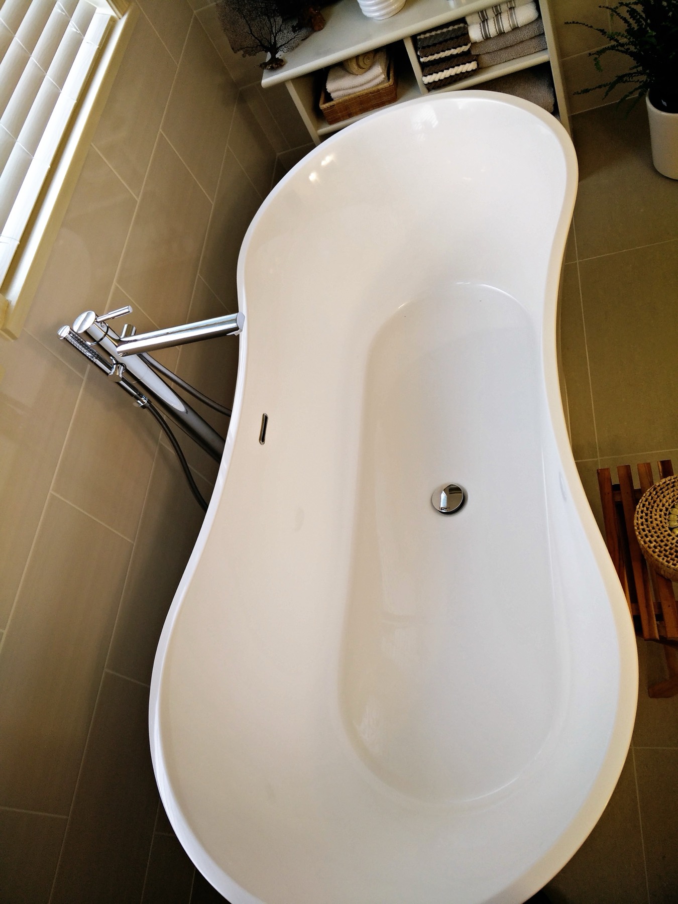Freestanding tub with a floor mounted filler on stone tile