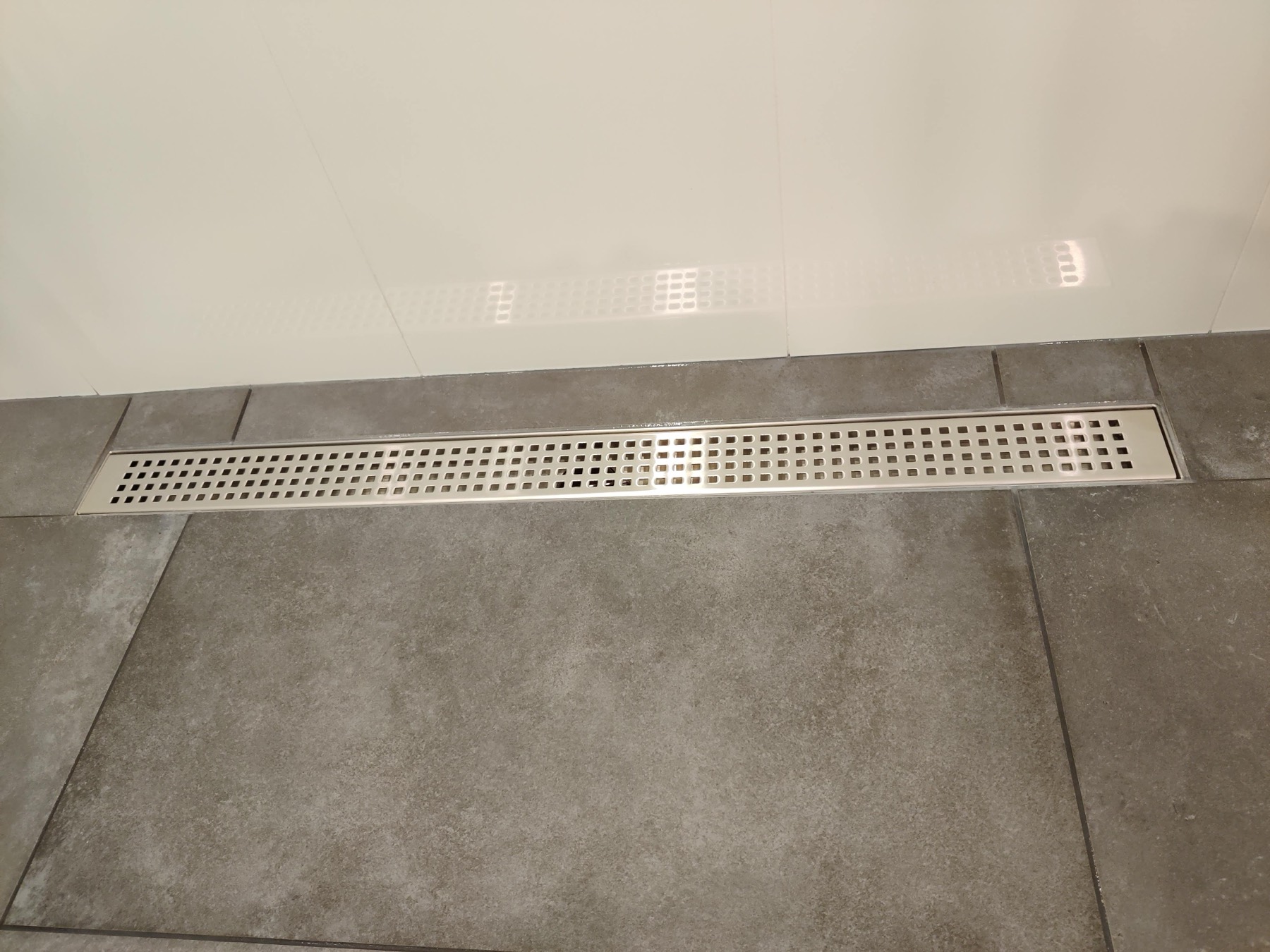 Linear drain set flush into a large format tiled shower floor